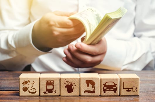 A man is counting money on the background of blocks with goods attributes. Import and export of goods and products. Retail and sales. Trade surplus, high purchasing power. Economic recovery. photo
