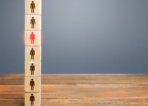 A red man stands out from a row number of people in a tower of blocks. Leader, leadership skills. Filling of vacancies with professional specialists. Staffing. Talented special essential employee. photo