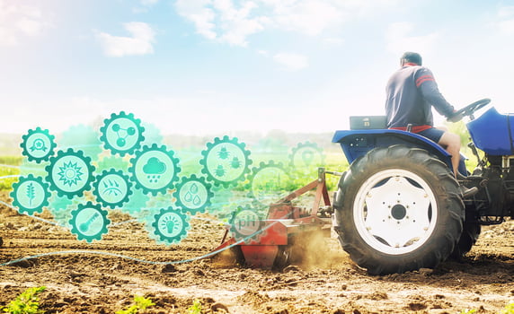 Farmer on a tractor cultivates a farm field and technological innovation gears hologram. Science of agronomy. Farming and agriculture startups. Improving efficiency. Soil milling, crumbling and mixing photo