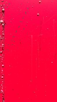 close-up of a vibrant crimson surface with scattered droplets and a vertical crack. photo