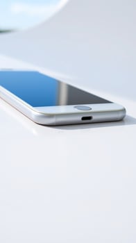 close-up of a silver smartphone with blue screen on a white surface photo