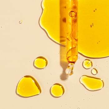 close up of yellow oil and a pipette flat lay on beige background photo
