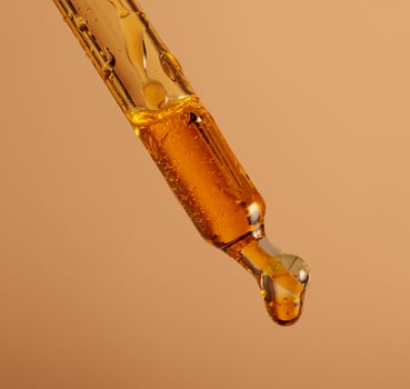 macro photo of a pipette filled with brown oil drop