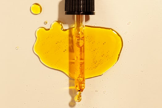 yellow oil flows out of the pipette flat lay on beige background photo