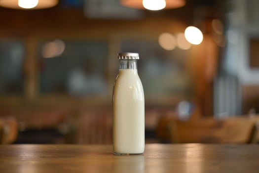 Glass milk bottle standing on wooden table in blurred restaurant background photo