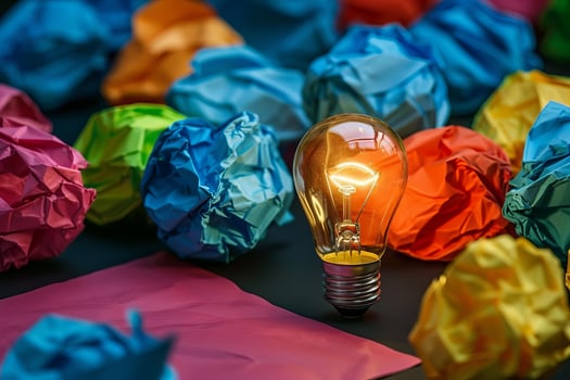 Glowing light bulb transforming crumpled colorful papers into creative ideas photo