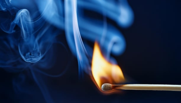 Burning match with bright flame and blue smoke on dark backdrop. photo