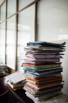 An office filled with stacks of document folders, creating a busy and organized workspace. photo