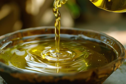 Pouring fresh olive oil into a rustic bowl creating golden ripples photo