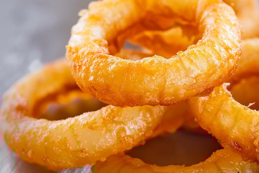 Delicious crispy onion rings stacked on metallic surface photo