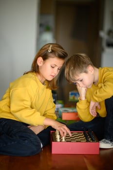 Children in yellow sweaters focus intently while playing chess on a wooden board. photo
