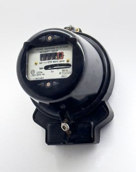 A close up of a vintage Soviet era single phase electric meter mounted on a white wall. The black housing and retro design emphasize its historical value and engineering significance photo