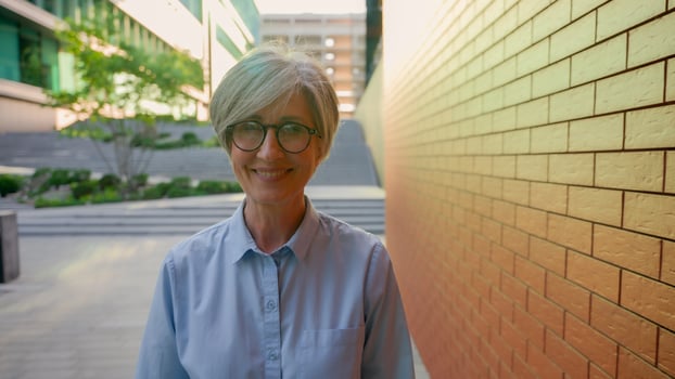 Caucasian old lady walking along city street senior mature female corporate professional employer businesswoman going to office business downtown smiling happy middle-aged woman tourist walk outdoors photo