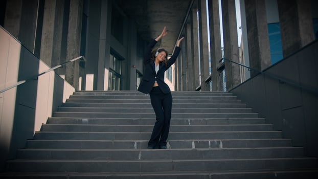 Dancing joyful happy funny Caucasian girl businesswoman listen music headphones enjoy song walking down stairs outside office building pleased professional business woman dance city freedom lifestyle photo