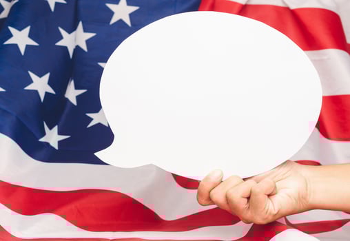 Hand holding of a blank white speech bubble over the American flag background photo
