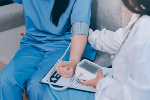 A woman in scrub clothes is holding a blood pressure monitor photo