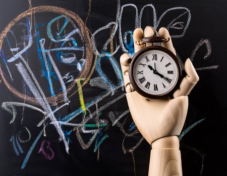 Time in Focus Wooden Hand Holding a Clock on Chalkboard Background photo