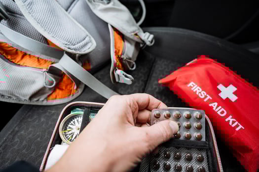 A person is carefully and methodically organizing and putting various pills into a first aid kit for easy access and to ensure that all necessary medications are available when needed photo