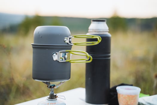 A Portable Camping Stove alongside a Thermos, beautifully displayed in a Scenic Outdoor Setting, perfect for your adventurefilled outings photo
