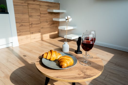 Enjoy a cozy breakfast with warm croissants and fine wine in a stylish living room filled with natural light, enhancing the ambiance photo