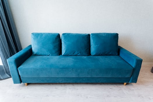 A blue couch in a room with a window photo
