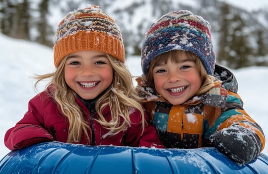 Two children in winter clothing sitting on a snow tube photo