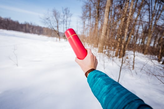 A person holding a red thermos in the snow photo