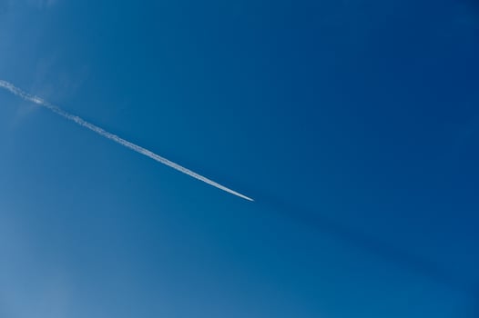 Contrails create delicate patterns across the bright blue sky during a sunny day photo
