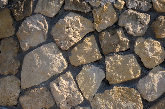 Natural stone wall showcasing rustic textures and earth tones in a sunlit outdoor setting photo