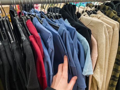 A person is thoughtfully selecting a stylish and fashionable shirt from a wellorganized rack in a trendy fashion store, in search of the ideal piece to enhance and elevate their wardrobe photo
