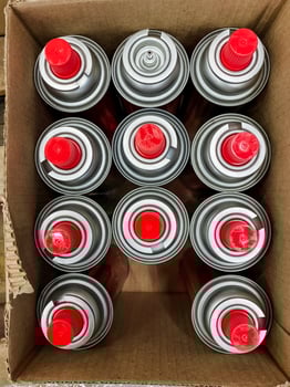 A box containing multiple spray paint cans, each distinguished by their bright red caps, suitable for various art and DIY projects, perfect for adding color to different surfaces photo