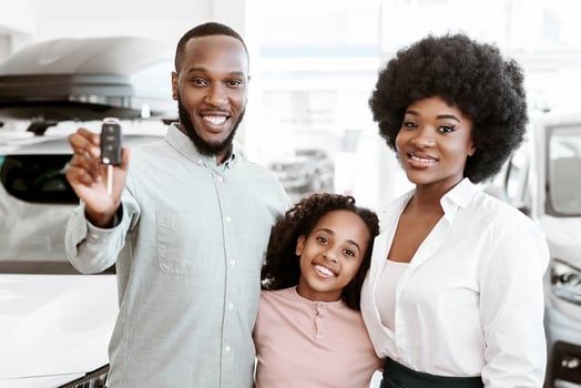Happy black family posing with new car key, buying or renting automobile at auto dealership. Cheerful African American parents and kid purchasing vehicle together at automotive showroom photo