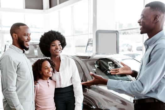 Car purchase or rental. Millennial black family with cute kid speaking to salesman about buying new automobile at dealership. African American manager showing his customers choice of autos at salon photo