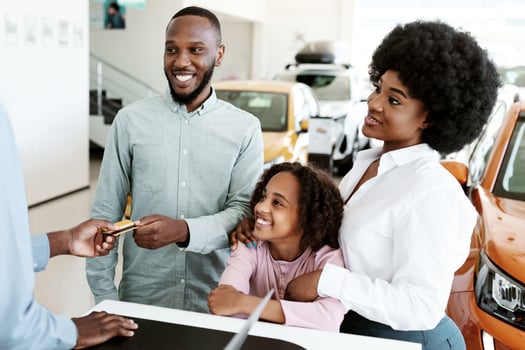 Happy black family paying for new car with credit card, buying auto from salesman at dealership store. African American customers purchasing automobile, using electronic money at showroom shop photo