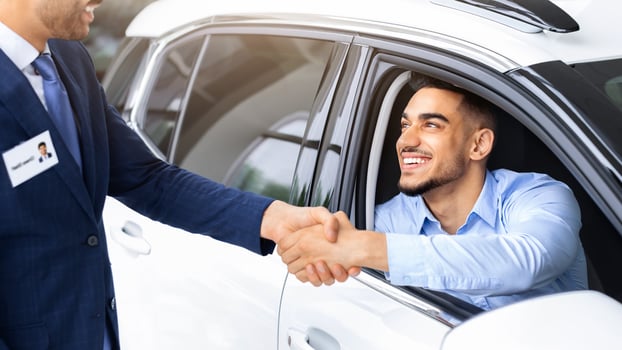 Happy middle-eastern man sitting in white luxury car shaking sales manager hand and smiling, celebrating successful deal. Closeup of arab guy buying brand new comfortable auto in showroom photo
