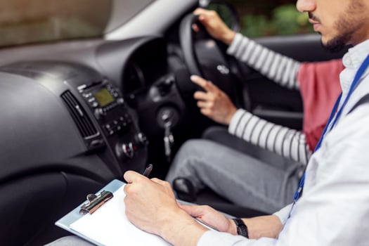 Serious young muslim guy teacher taking driving test from woman in hijab at steering wheel driving car, cropped. Mentor teaches student to drive, driving class and good mark. Education and study photo