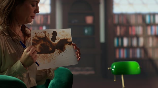 Military veteran studies Rorschach inkblot in therapy session with counselor, addressing PTSD and trauma recovery problems. Woman shows psychological support for mental health care. Camera B. photo
