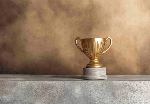 Golden trophy on gray surface against brown background photo