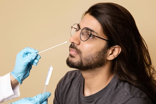 Coronavirus, COVID-19 pcr test concept. Nurse taking nasal swab for coronavirus sample test from potentially infected middle-eastern guy, beige studio background, closeup, copy space photo