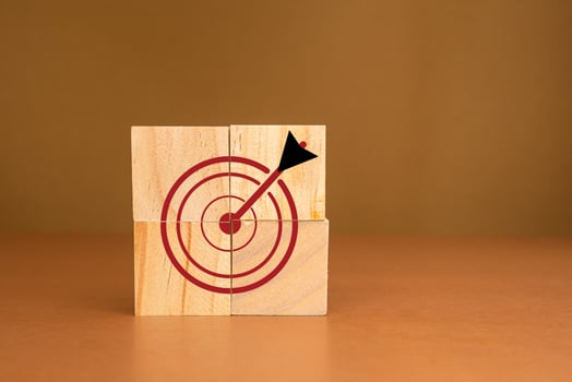 Focus on a goal and achieve a successful business. Darts target icons on wooden cubes against a brown background photo