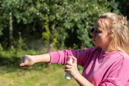 Woman applying insect repellent mosquito insecticide spray to kill flies bugs and mosquitoes on skin outside. Malaria zika virus and dengue fever prevention. Protective measures photo