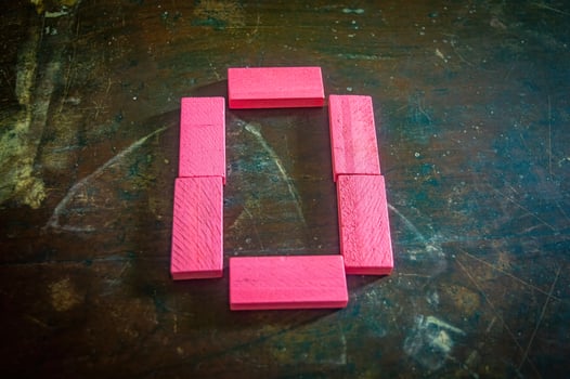 Red wooden blocks arranged in the shape of the number zero on a rustic wooden surface. Perfect for educational, numerical, or creative concepts photo