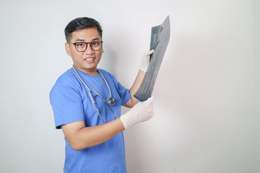 Happy asian doctor looking at x-ray photo