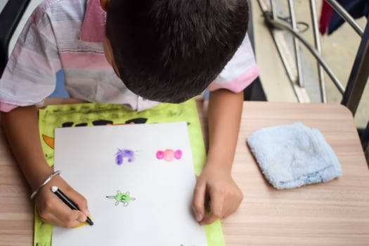 A young boy is drawing on a piece of paper photo