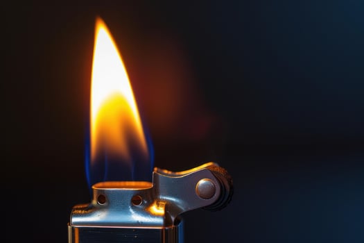 Metal lighter burning with bright yellow and blue flame on dark background photo