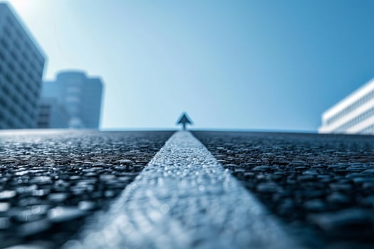 White line and arrow pointing forward on asphalt road between buildings photo