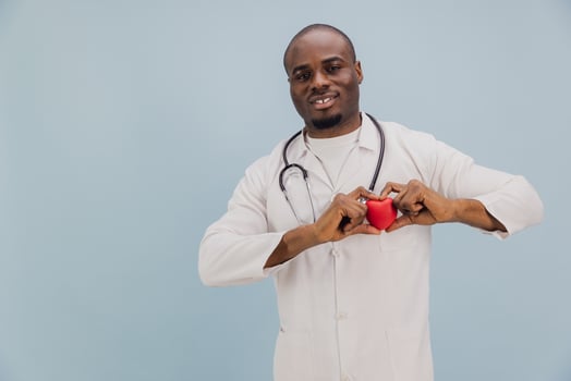 Smiling African American Doctor Holding Red Heart on Blue Background photo
