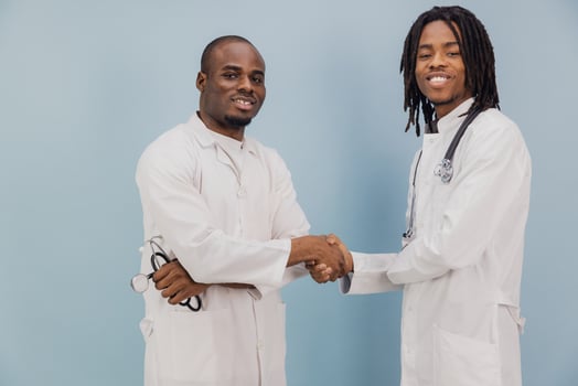 Two Young African American Doctors Shaking Hands on Blue Background photo