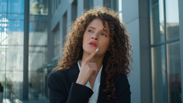 Pensive Caucasian girl young 20s business woman thinking problem solution hold hand on chin brainstorm think idea in city outside thoughtful puzzled businesswoman uncertain difficult question doubt photo