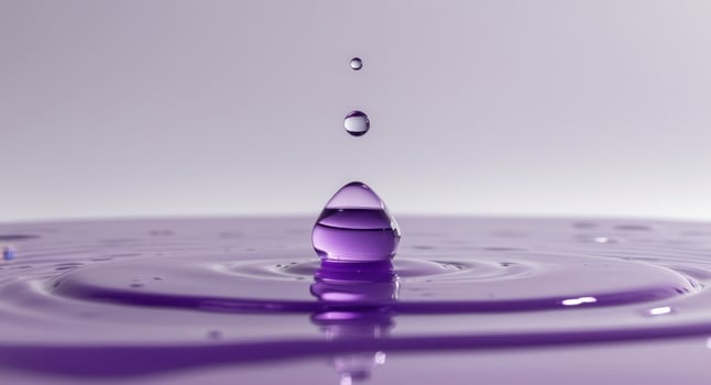 Purple water droplet resting on the surface of a vibrant purple liquid pool. photo